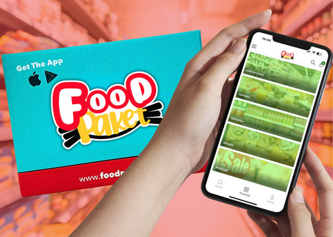 Ein Paket von Foodpaket und ein Smartphone mit der geöffneten Foodpaket-App wird gezeigt.